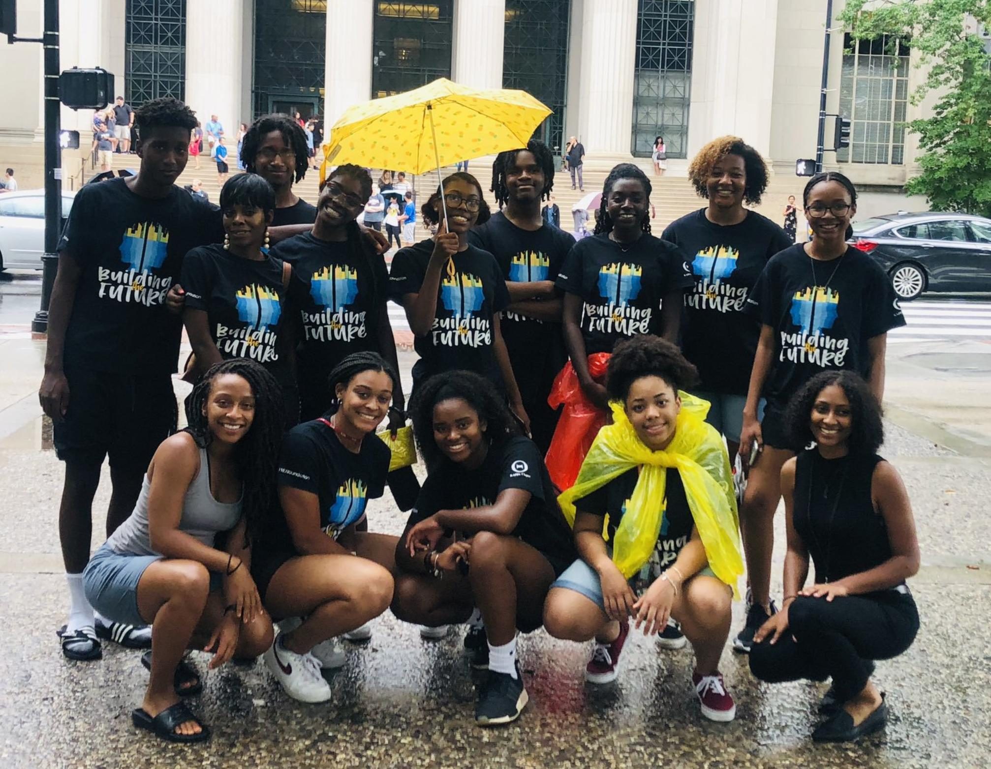 REEX program high school students of color posing in the rain in front of 77 Massachusetts Ave.