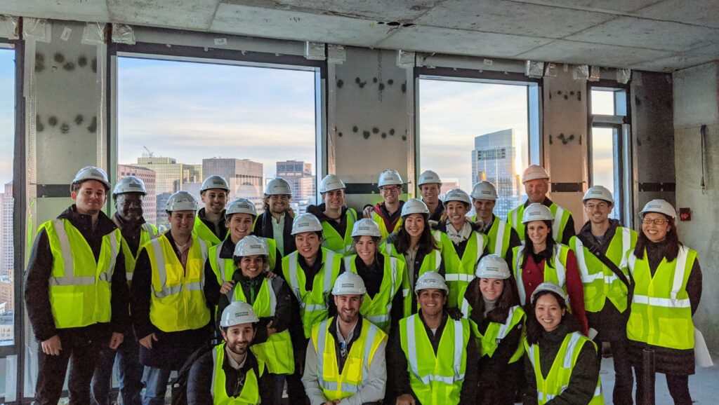 class photo of masters students touring alum Ollie carr's building under-development