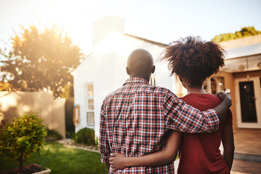 Rear view shot of a young couple admiring their new house outside